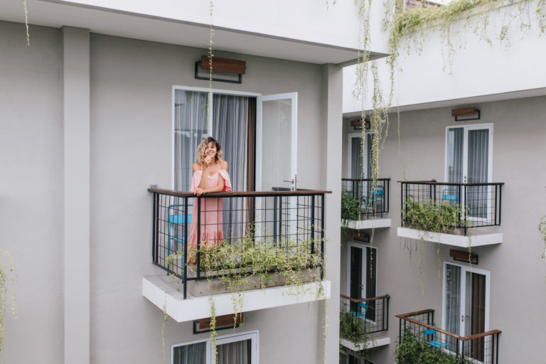 Wonderful caucasian girl expressing happiness while posing in hotel. Photo of carefree curly tanned woman in pink dress.
